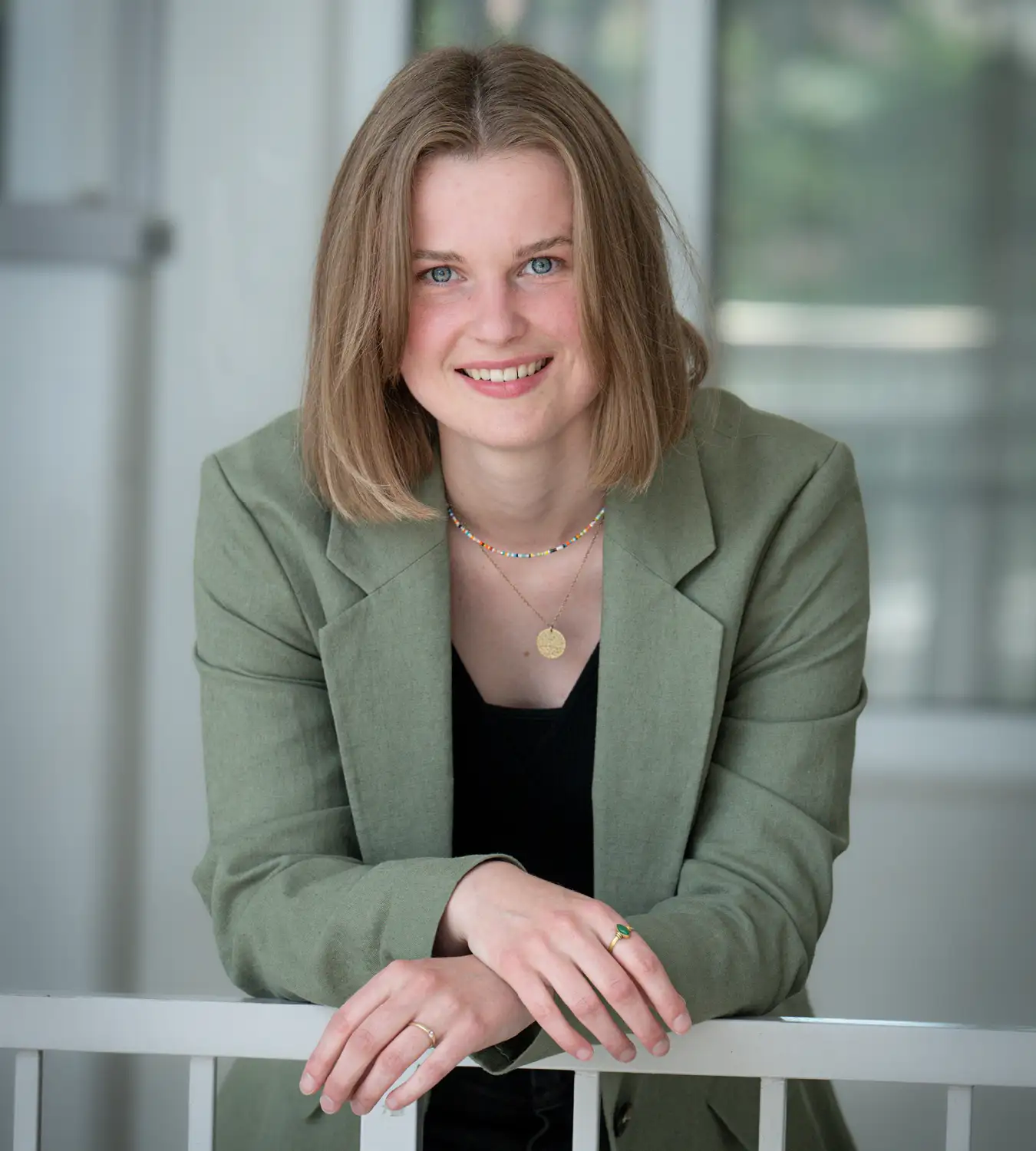 Auf diesem Bild sehen Sie eine junge Frau im Anzug, die sich an einem Geländer abstützt
